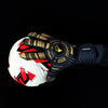 A close-up of high-performance goalkeeper gloves with gold and black accents, shown gripping a soccer ball against a black ba