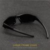 Une paire de lunettes de soleil noires à monture large posée sur une surface sombre et mouchetée.