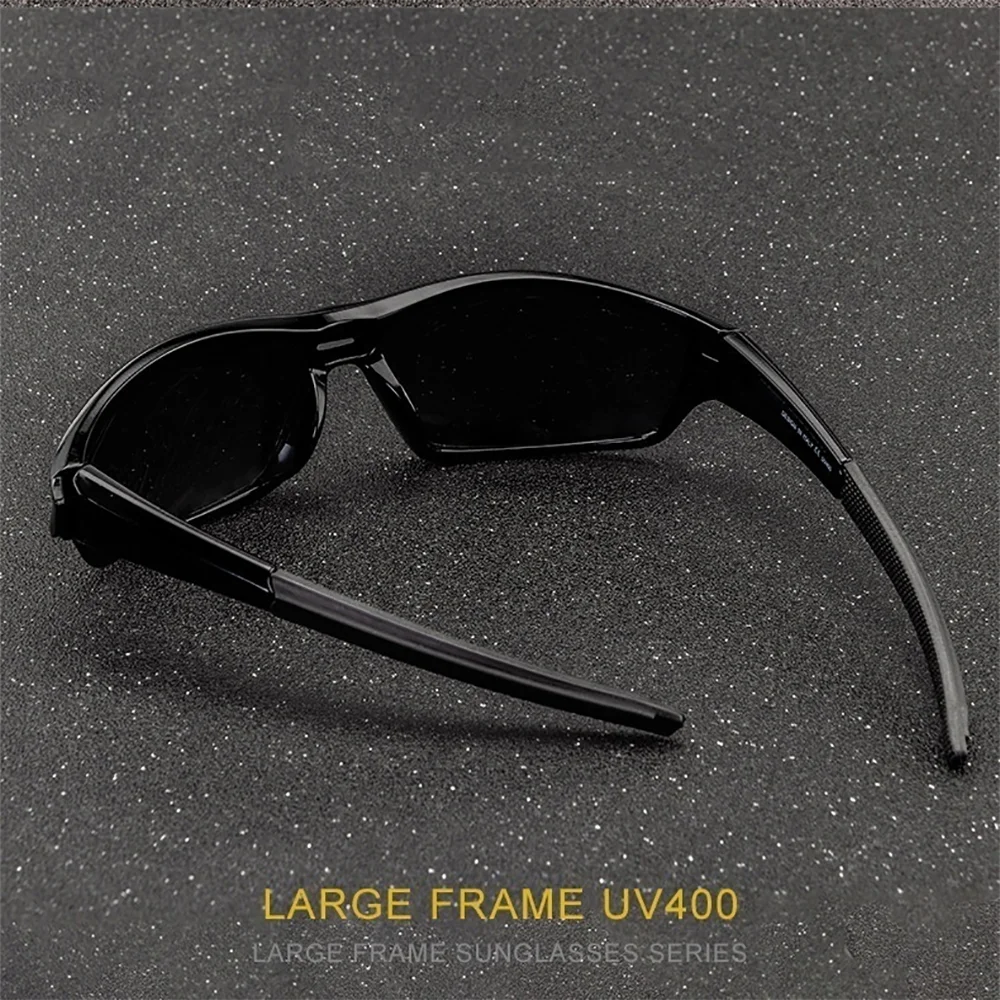 Une paire de lunettes de soleil noires à monture large posée sur une surface sombre et mouchetée.