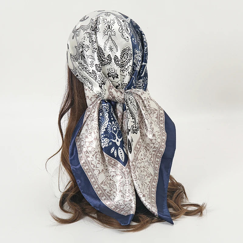 Elegant satin square scarf featuring intricate paisley patterns in silver, white, and navy blue.