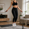 A woman performing a home workout using an adjustable weighted speed jump rope in a bright living room.