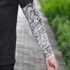 Close-up of a person's arm displaying intricate black and white traditional tattoo sleeve designs.