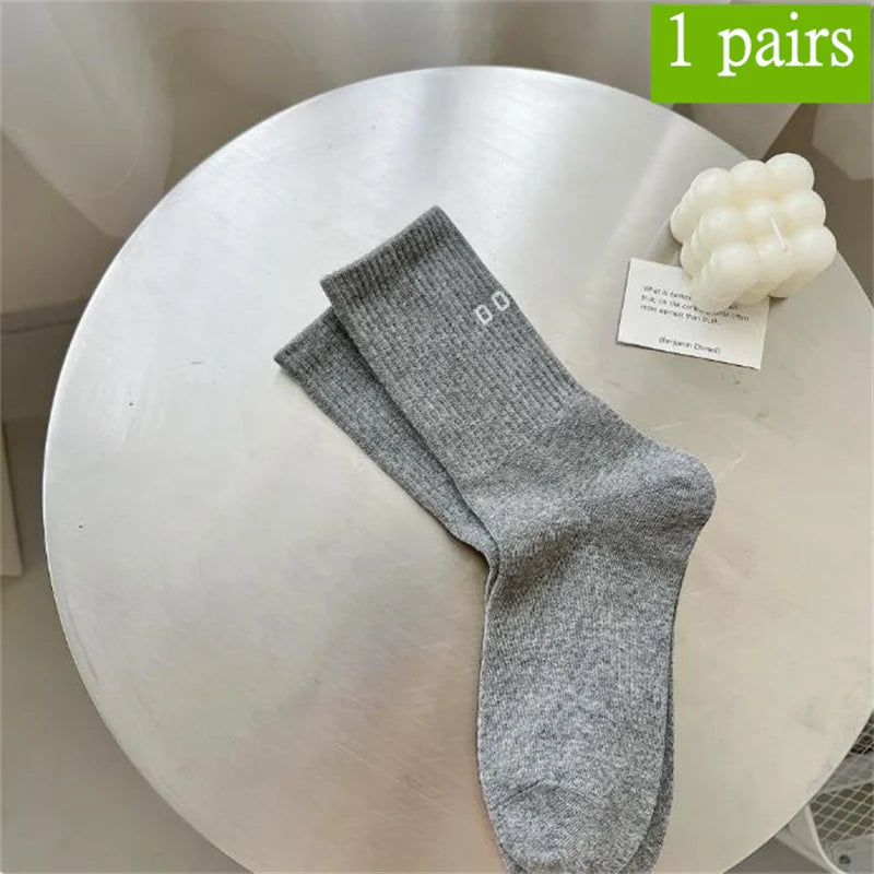 Ein Paar grauer atmungsaktiver rutschfester Yoga- und Fitnesssocken auf einem weißen Tisch.