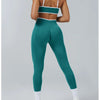A woman wearing teal high-waist yoga leggings with a white band and white socks.