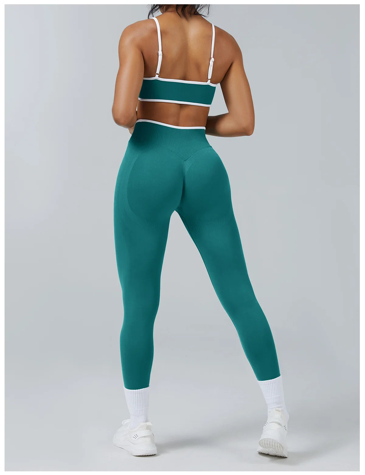 A woman wearing teal high-waist yoga leggings with a white band and white socks.