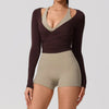 A woman wearing a dark brown long sleeve top and matching high-waisted shorts for yoga or sport.