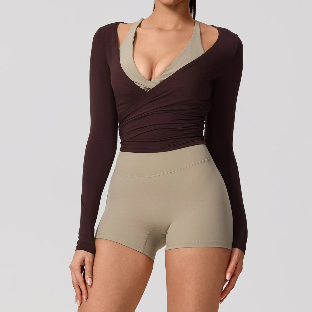 A woman wearing a dark brown long sleeve top and matching high-waisted shorts for yoga or sport.
