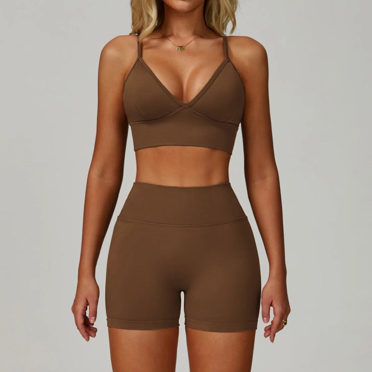Eine Frau modelliert ein nahtloses Sport-Yoga-Set in Braun, bestehend aus einem Crop-Top und hohen Shorts.