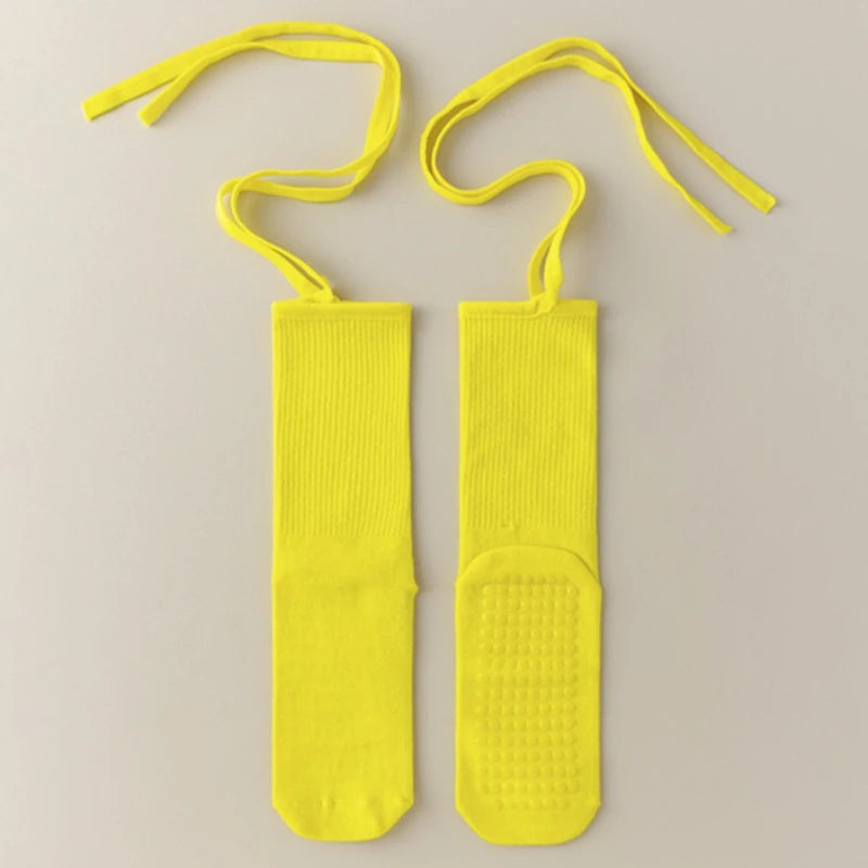 A pair of bright yellow silicone anti-slip yoga socks with elastic drawstrings.