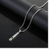 A silver stainless steel whistle pendant necklace with a chain is displayed against a dark background.