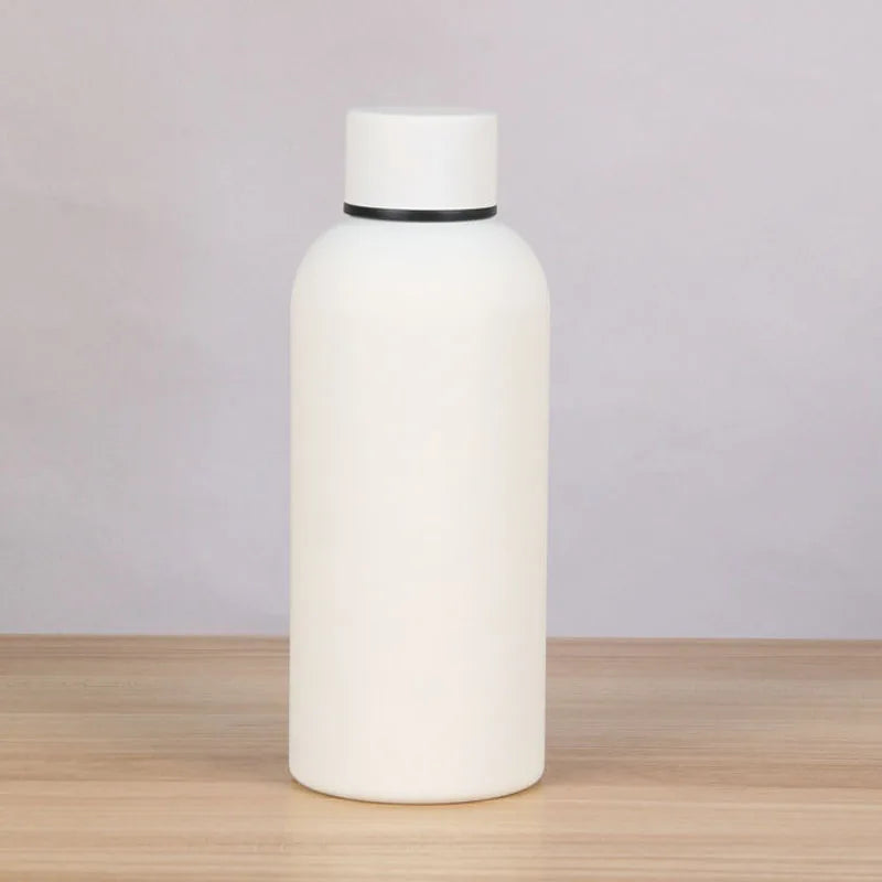 A white double-layer vacuum thermos cup with a black lid sitting on a wooden surface.