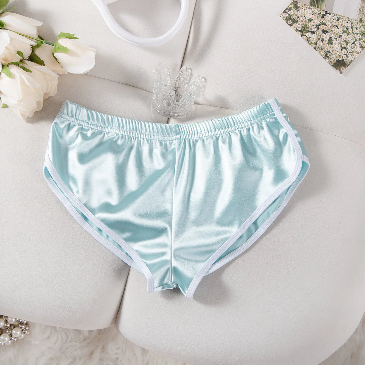 Hellblaue Satin-Runningshorts für Damen mit elastischem Bund, flach auf weißer Oberfläche.