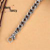 A silver mantra charm bracelet with a link chain and a round charm is displayed on a light brown background.