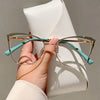A hand holds a pair of light blue cat-eye glasses against a white leather product.