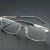 A pair of silver-framed reading glasses with dark gray frames and clear lenses resting on a dark surface.