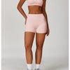 A woman models a pink 3-piece yoga sports set consisting of a crop top, brief, and shorts.