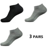 Tres pares de calcetines deportivos de algodón gris y negro para el tobillo, vistos de lado.