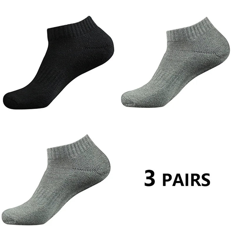 Tres pares de calcetines deportivos de algodón gris y negro para el tobillo, vistos de lado.