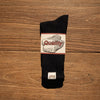 A black tube sock with a white and red graphic that reads Quality
