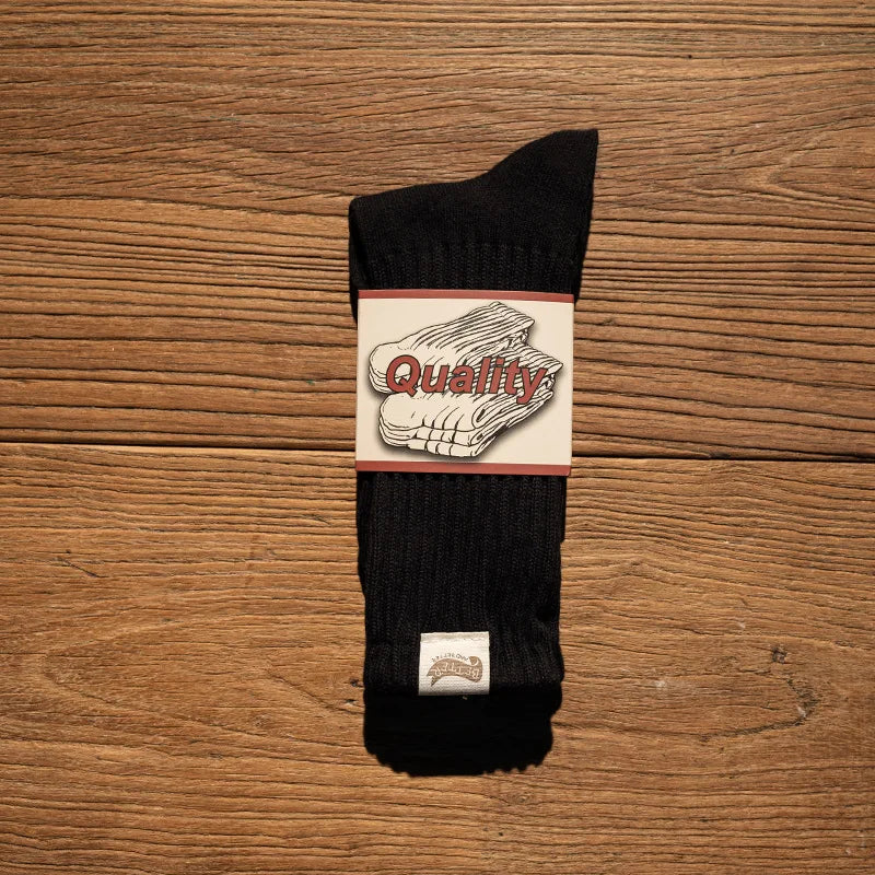 A black tube sock with a white and red graphic that reads Quality