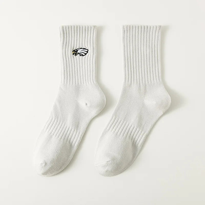 A pair of white men's athletic crew socks with a black embroidered logo on the calf.