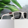 White polarized square sunglasses resting on a white surface with green foliage in the background.