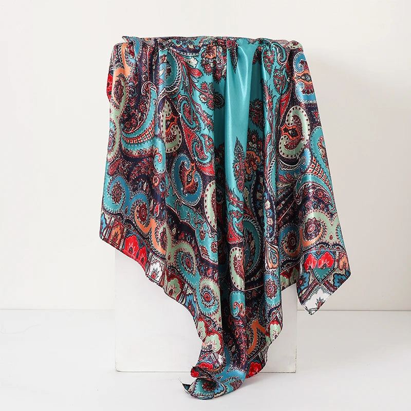 A flowing women's silk paisley shawl scarf in shades of teal, rust, and deep red.