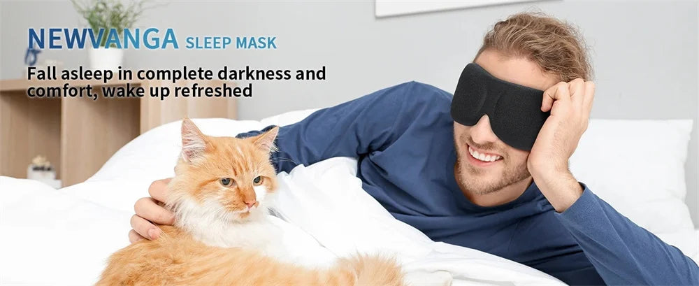 A man wearing a black sleep mask is resting in bed with an orange cat beside him.