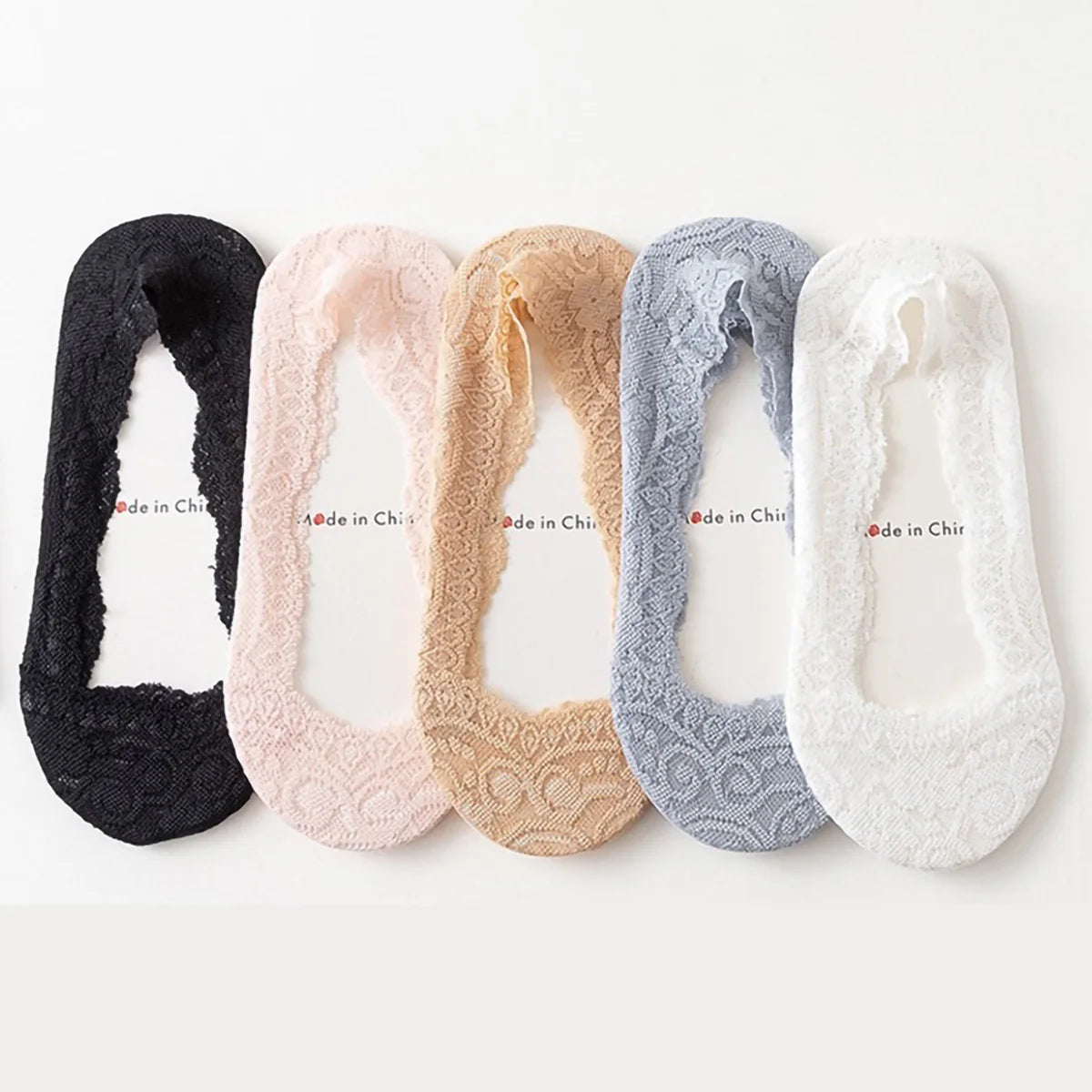 Un set de cinco calcetines invisibles de silicona no-show para mujer en varios tonos: negro, rosa, beige, gris y blanco.