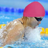 Une personne portant un bonnet de bain rose éclabousse l'eau tout en nageant.