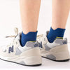 A pair of light gray athletic shoes with blue socks are shown against a white background.