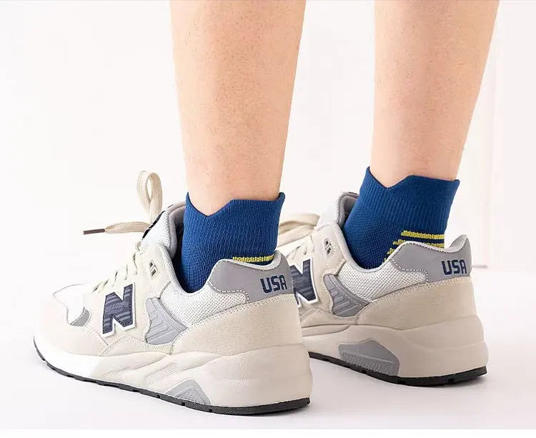 A pair of light gray athletic shoes with blue socks are shown against a white background.