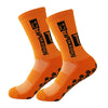 A pair of orange anti-slip performance sports socks with black text and rubberized dots.