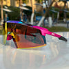 A pair of vibrant purple and orange sports sunglasses resting on a white surface.