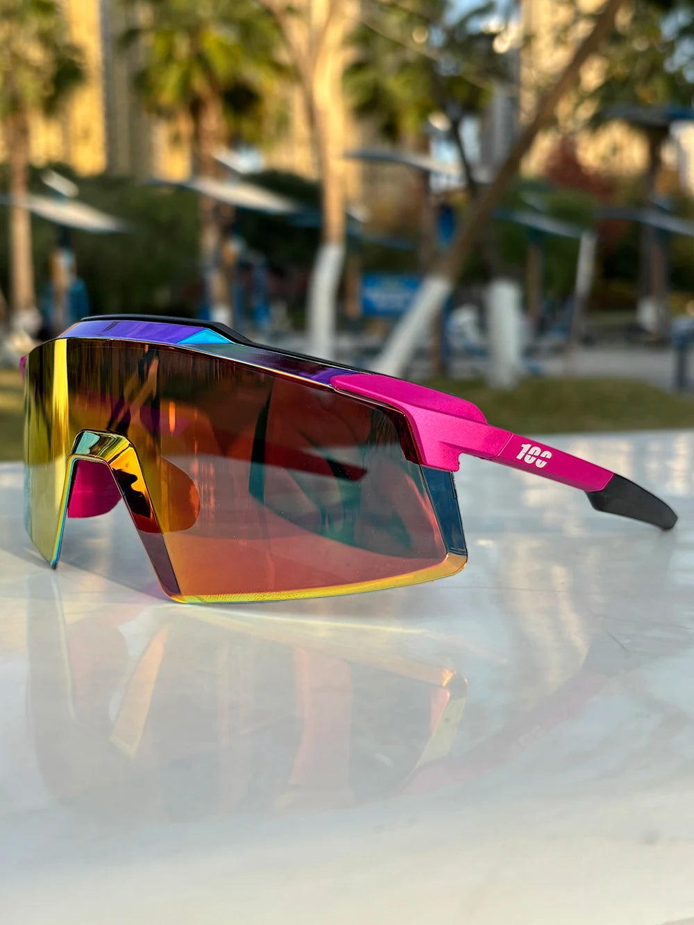 A pair of vibrant purple and orange sports sunglasses resting on a white surface.