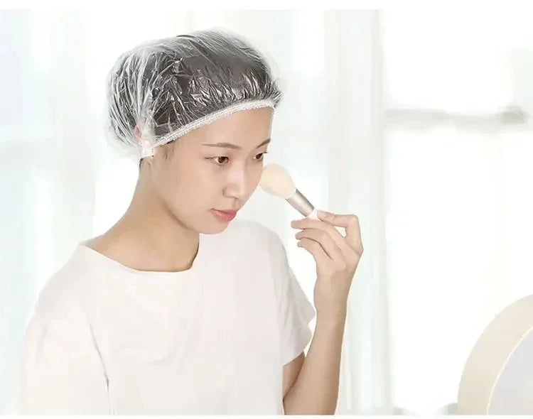 Una mujer está aplicando gorros de ducha desechables transparentes en su cabello para extensiones o trenzas.