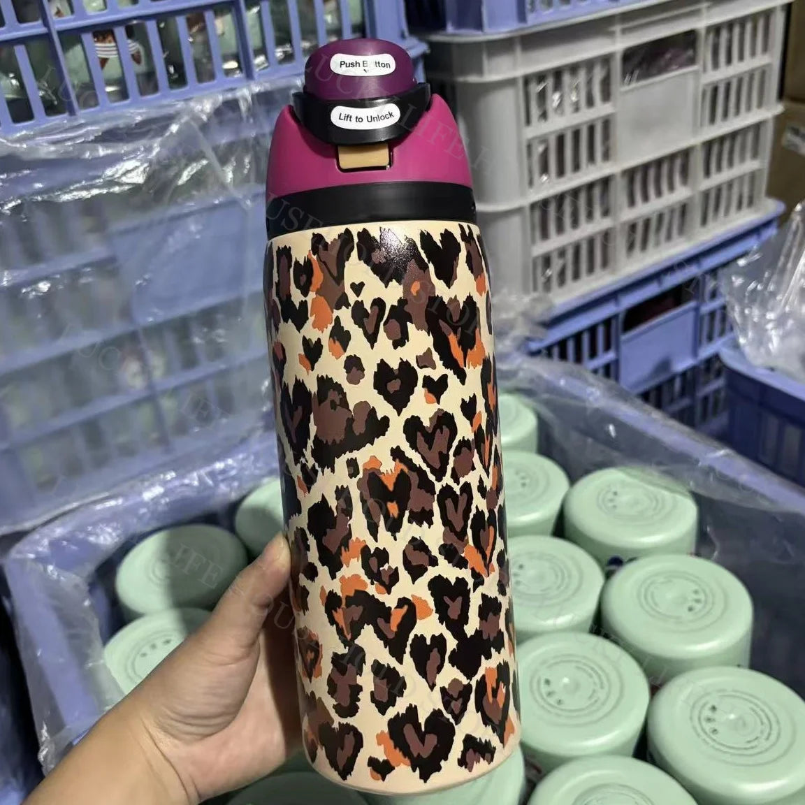 A hand holds a purple and brown leopard print insulated stainless steel sports water bottle.