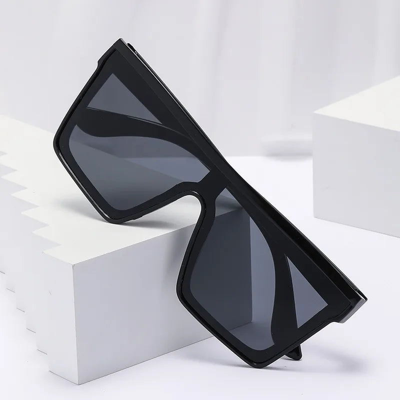 Black retro square sunglasses resting on a white block.
