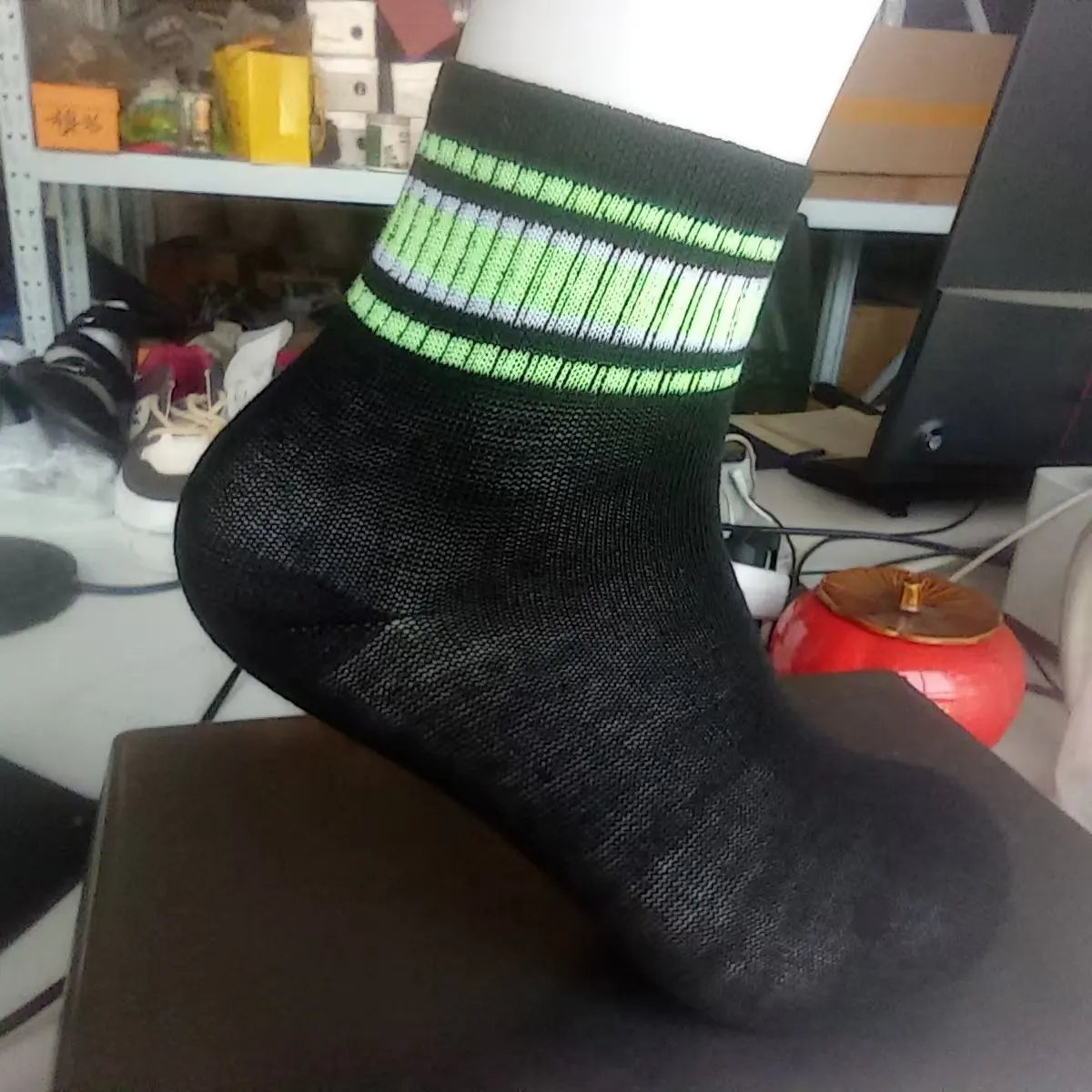 A black sock with neon green stripes on the cuff displayed on a dark surface.