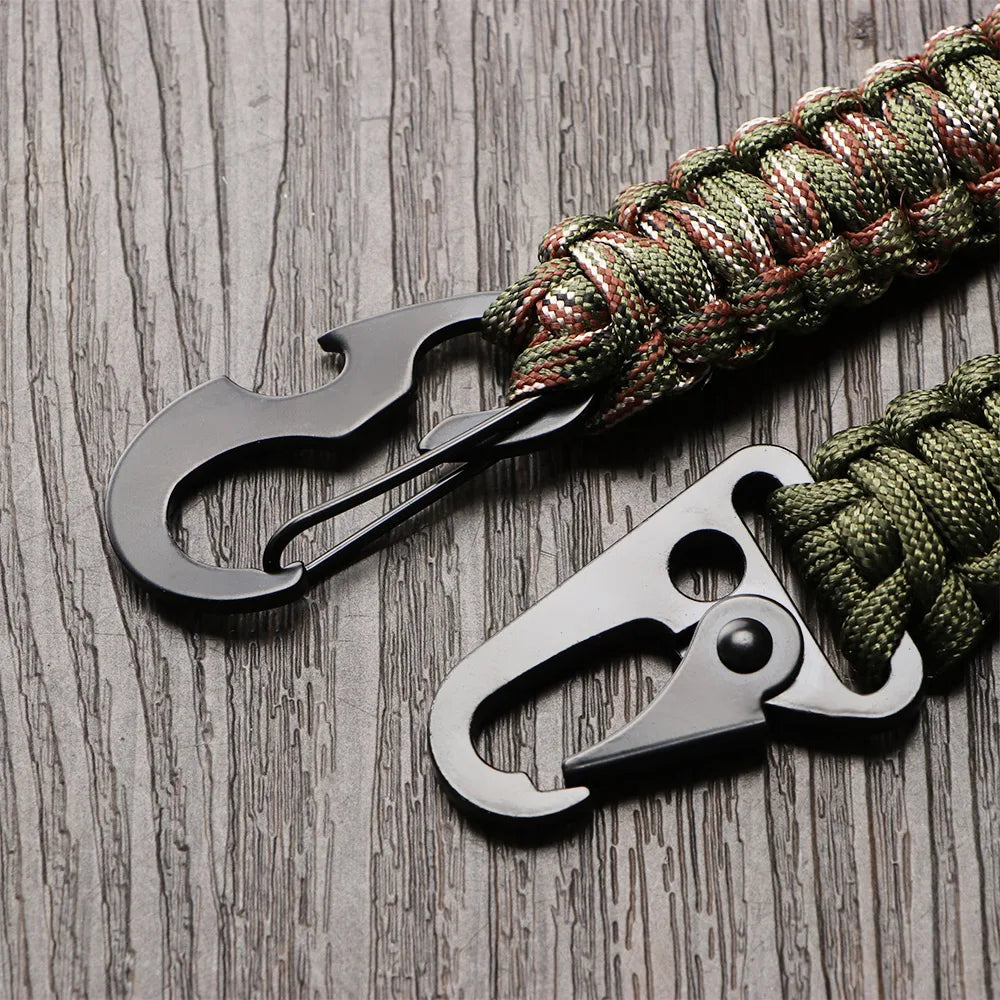 A close-up of a multi-tool keychain featuring a black scissor-style opener attached to a green and red braided cord.