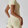 A model wearing a seamless, light beige yoga jumpsuit in a fitted style.