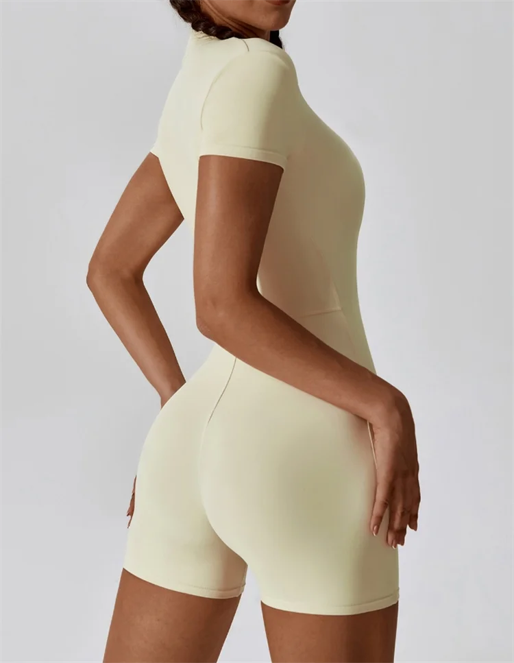 A model wearing a seamless, light beige yoga jumpsuit in a fitted style.