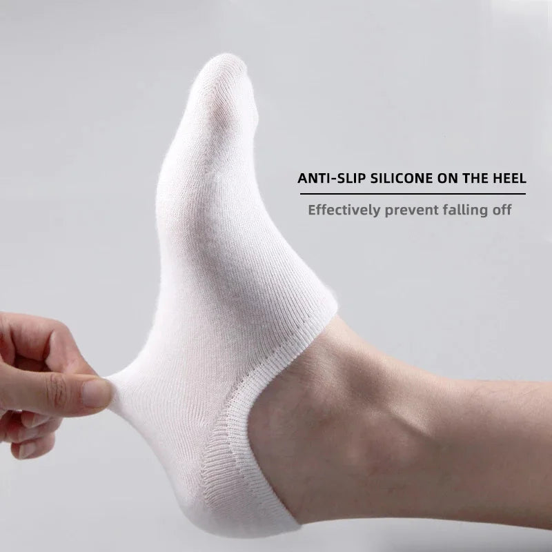 A close-up of a person's foot wearing white silicone no-show socks with an anti-slip grip on the heel.
