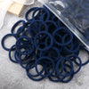 A pile of dark blue elastic hair bands with a clear plastic container in the background.