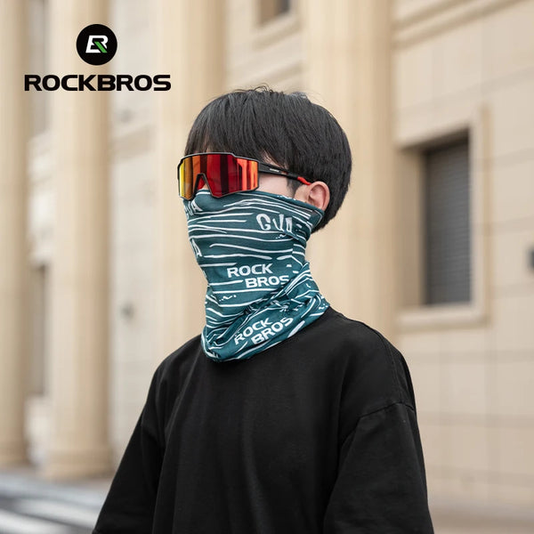 A boy wearing a green and white face mask and sunglasses, standing outdoors.