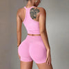 A woman models a bright pink two-piece yoga set featuring a racerback tank top and matching shorts.