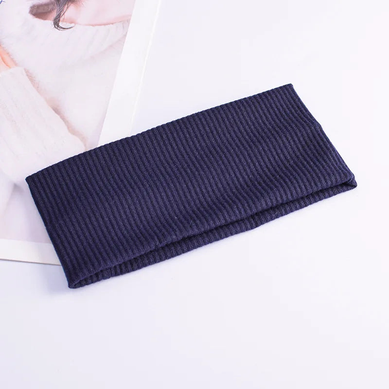 A dark navy knitted headband lying on a white surface.