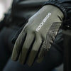Close-up of olive green cycling performance gloves with black stripes on a hand, worn by a person.