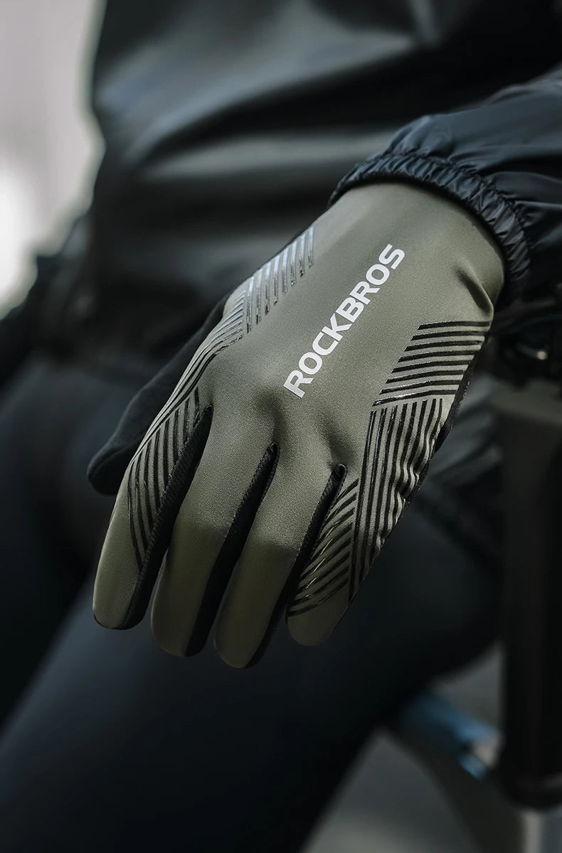 Close-up of olive green cycling performance gloves with black stripes on a hand, worn by a person.