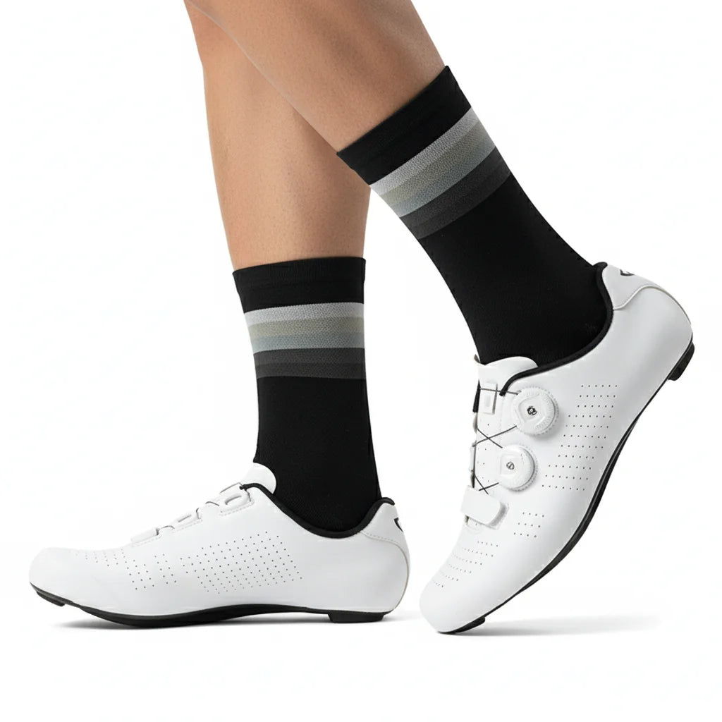 A pair of white cycling shoes and black socks with gray stripes are shown on a white background.